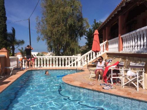 grupa ludzi siedzących w fotelach obok basenu w obiekcie Villa climatisée, piscine w mieście Jeresa