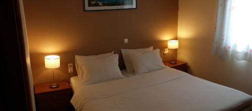 a bedroom with a large white bed with two lamps at Valley Village in Matala