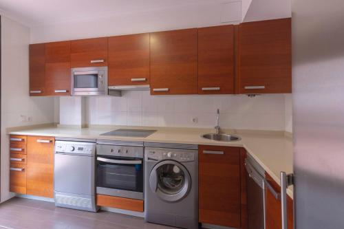 a kitchen with a washing machine and a microwave at Apartamentos Verdemar (VUT) in Llanes