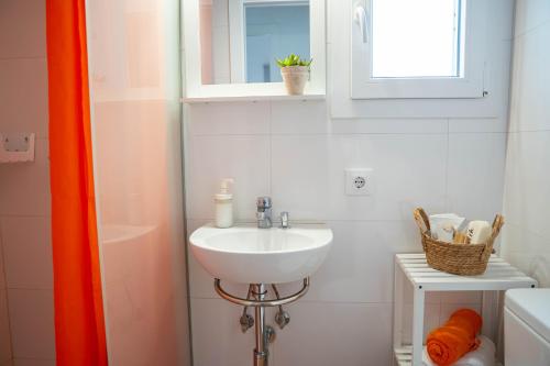 een witte badkamer met een wastafel en een raam bij Casa Menorquina centro Ciutadella in Ciutadella