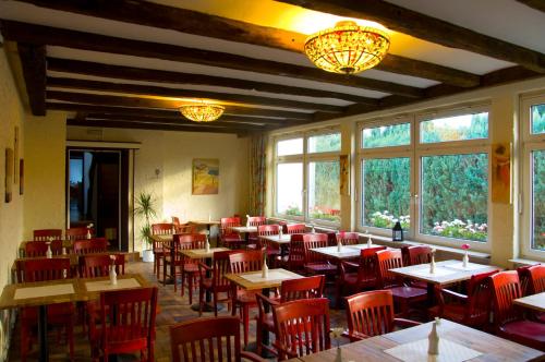 un restaurante con mesas, sillas rojas y ventanas en Hotel Kölner Hof Refrath, en Bergisch Gladbach