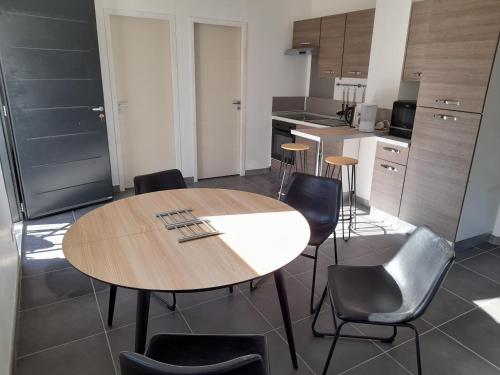une cuisine avec une table et des chaises en bois dans l'établissement Studio du Roc des Garrigues, à Langlade