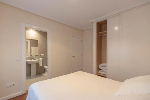 a white bedroom with a bed and a sink at Apartamentos Verdemar (VUT) in Llanes