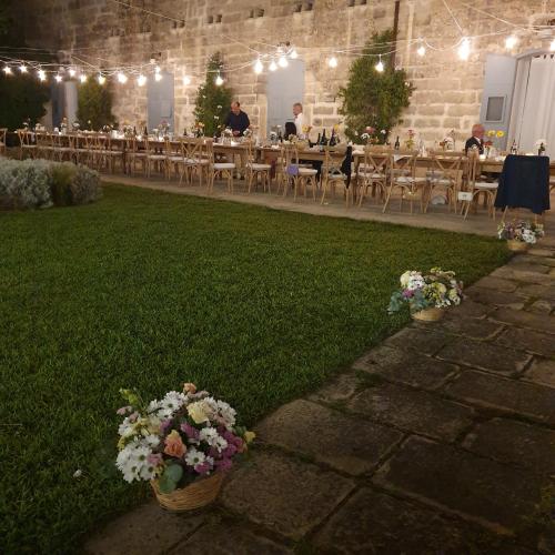 a room with tables and chairs and flowers on the grass at Masseria Spartivento in Conca Specchiulla