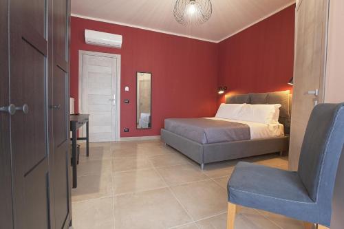 a bedroom with red walls and a bed and a chair at Malù - Bed & Breakfast in Agrigento