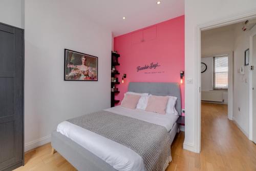 1 dormitorio con 1 cama grande y pared de color rosa en The Lipstick Palace - Fitzrovia - by Frankie Says en Londres
