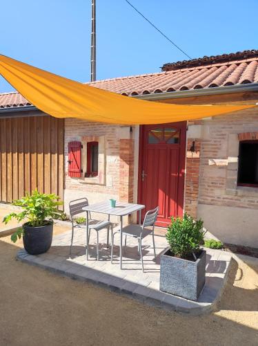 d'une terrasse avec une table, des chaises et une porte rouge. dans l'établissement Studio de charme indépendant, à Belin-Beliet