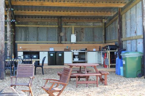 einen Picknicktisch und Stühle in einer Scheune in der Unterkunft Cattlestone Farm in Coolham
