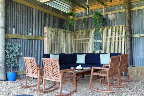 un patio con un sofá azul y sillas en Cattlestone Farm en Coolham