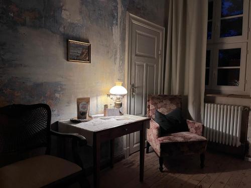 a desk with a lamp and a chair in a room at Gut Manderow an der Ostsee in Hohenkirchen