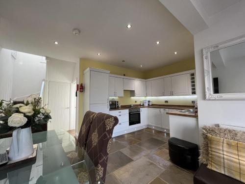 een keuken met witte kasten en een glazen tafel bij 3 Bedrooms 2 Bath Cottage Balcony Garden Dogs Free in Berwick-Upon-Tweed