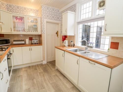 a kitchen with white cabinets and a sink at Beausite in Colwyn Bay