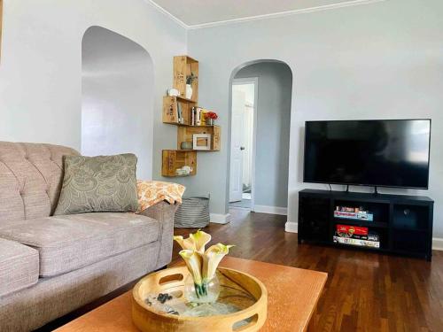 a living room with a couch and a flat screen tv at Green Roof Inn - Centrally Located 2BR/1BA Home in Evansville