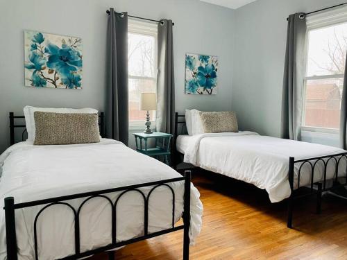 a bedroom with two beds and two windows at Green Roof Inn - Centrally Located 2BR/1BA Home in Evansville