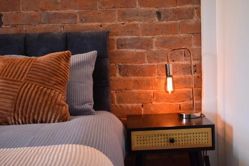 a bed with a lamp on a table next to a brick wall at Entire house in Retford city centre in Retford