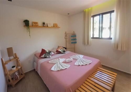 1 dormitorio con cama rosa y ventana en Residencial Villa Jeri 2 SUÍTES a 300m do MAR, VARANDA, Smart TV, Wi-Fi, ar-condicionado en Jericoacoara