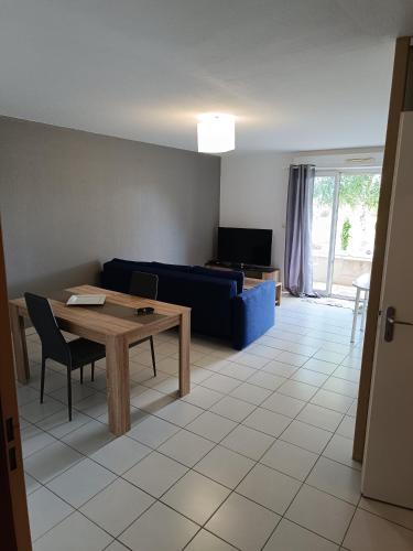 sala de estar con mesa y sofá azul en Appartement T2 en Limoges