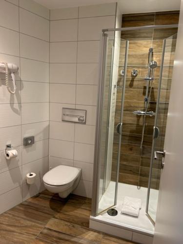 a bathroom with a toilet and a glass shower at Hotel Kaiserhof in Siegburg