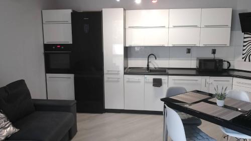 a kitchen with white cabinets and a table and a couch at Apartament Zalesie z tarasem in Lubin