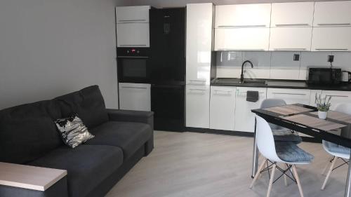 a living room with a couch and a table and a kitchen at Apartament Zalesie z tarasem in Lubin