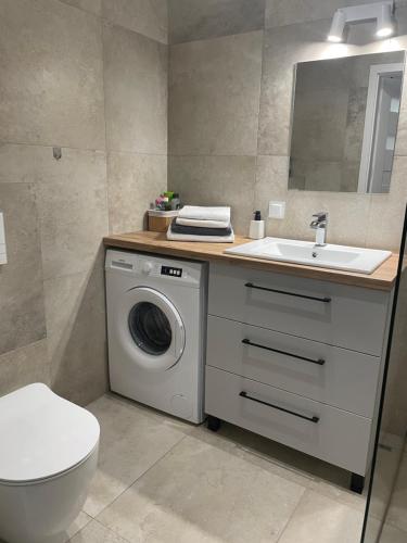 a bathroom with a washing machine and a sink at Apartament Tęczowa in Gdynia