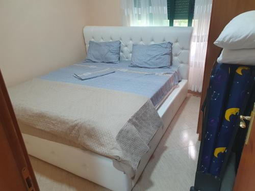 - un lit blanc avec des oreillers bleus dans l'établissement Pine Trees Veranda, à Golem