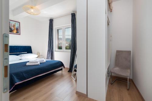 ein Schlafzimmer mit einem blauen Bett und einem Stuhl in der Unterkunft Apartment East in Kaštela