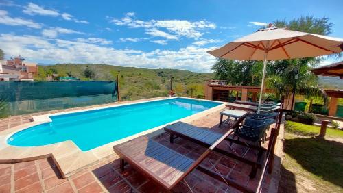 una piscina con ombrellone, tavolo e sedie di Sierras Cabañas a Villa Carlos Paz