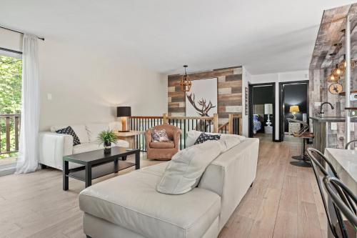 a living room with a white couch and a table at Le Panaché-Chalet à louer Stoneham in Stoneham
