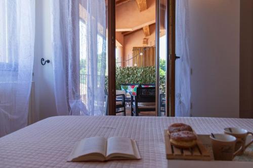 una mesa con un libro y un plato de donuts en ella en Anemoni Home nel Borgo di Montegridolfo by Yohome, en Montegridolfo