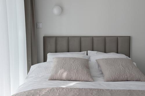1 cama con sábanas blancas y 2 almohadas en Rewal HEVENIA Premium Baltic Apartment with SPA access, en Rewal
