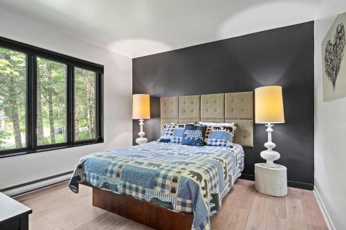 a bedroom with a bed with two lamps on it at Le Panaché-Chalet à louer Stoneham in Stoneham