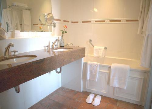 a bathroom with two sinks and a tub with towels at Chambres d'hôtes Relais Mira Peis in Mirepoix