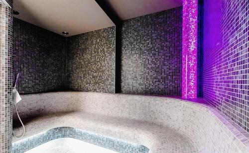 y baño con bañera con iluminación púrpura. en Rewal HEVENIA Premium Baltic Apartment with SPA access, en Rewal