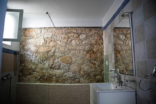 a bathroom with a stone wall and a sink at Pines & Sea Studio in Áyioi