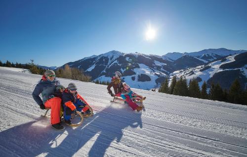 a group of people riding on a sled in the snow at Hotel Neuhaus in Saalbach Hinterglemm