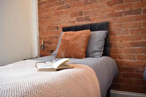 uma cama com um livro e óculos e uma parede de tijolos em Entire house in Retford city centre em Retford