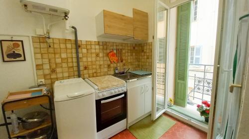 Il comprend une petite cuisine avec une cuisinière et une fenêtre. dans l'établissement Charmant studio, à Cannes