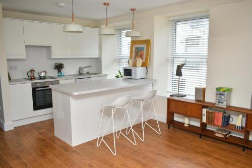 a kitchen with white cabinets and white counter stools at Berlin Wall Apartment at The Residence Bantry in Bantry