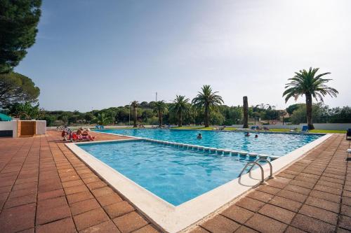 una grande piscina con persone sedute intorno di Kampaoh Palamós Internacional a Palamós