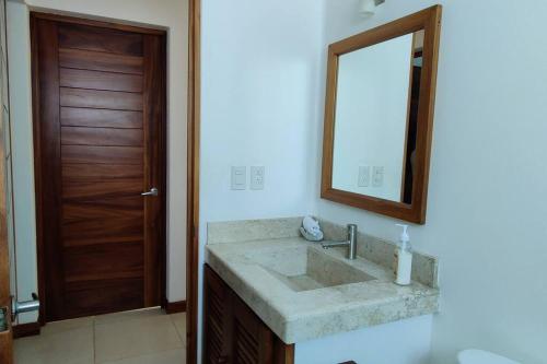 ein Badezimmer mit Waschbecken, Spiegel und Tür in der Unterkunft Apartment Tortugas - rooms with AC and great pool at 5 min from Carrizalillo beach and Benito Juarez Bulevard in Puerto Escondido