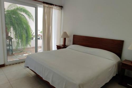 ein Schlafzimmer mit einem großen Bett und einem großen Fenster in der Unterkunft Apartment Tortugas - rooms with AC and great pool at 5 min from Carrizalillo beach and Benito Juarez Bulevard in Puerto Escondido