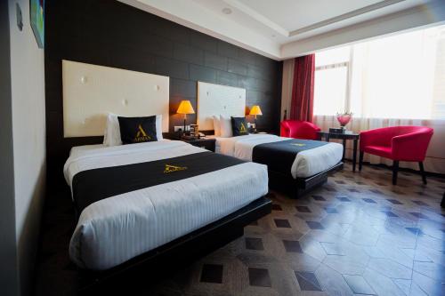 a hotel room with two beds and red chairs at Arman Hotel Juffair Mall in Manama