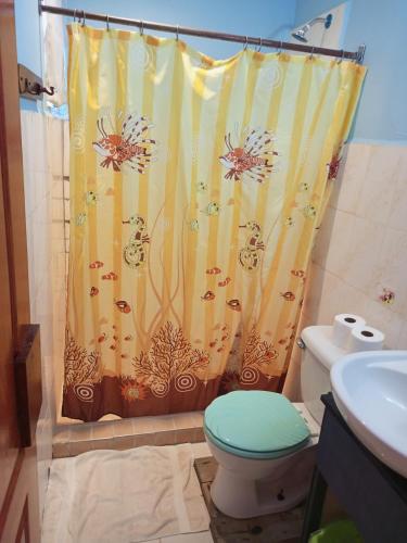 a bathroom with a shower curtain and a toilet at Surfari Bocas in Bocas del Toro