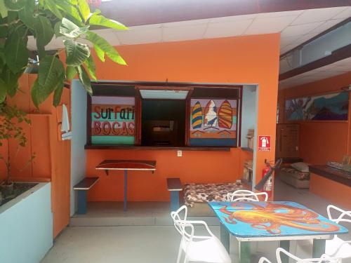 a room with an orange wall with a table and chairs at Surfari Bocas in Bocas del Toro