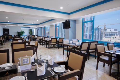 a restaurant with tables and chairs and a large window at Arman Hotel Juffair Mall in Manama