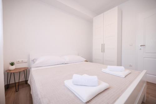Un dormitorio blanco con una cama con toallas. en New Family Apartments with private parking near Zadar en Murvica