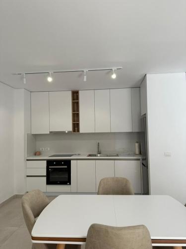 a kitchen with white cabinets and a table and chairs at EME APARTMENTS - Kompleksi San Pietro, Gjiri i Lalzit in Durrës