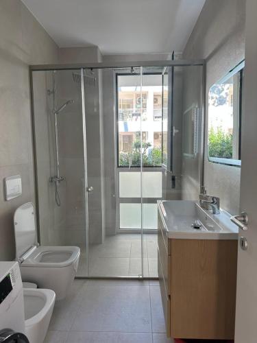 a bathroom with a shower and a toilet and a sink at EME APARTMENTS - Kompleksi San Pietro, Gjiri i Lalzit in Durrës