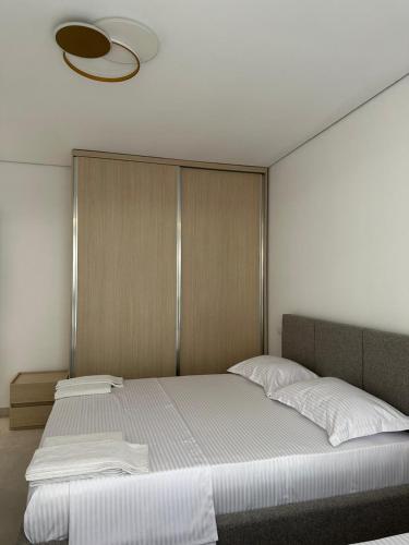 a bedroom with a large white bed with a ceiling at EME APARTMENTS - Kompleksi San Pietro, Gjiri i Lalzit in Durrës